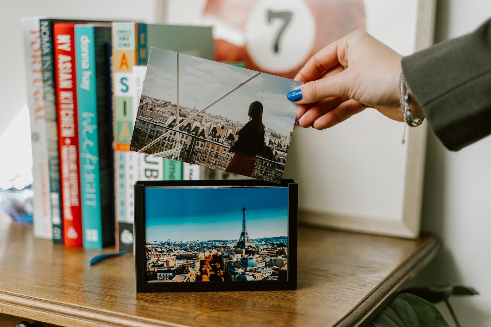 een vrouwenhand wisselt een foto in het wissel frame die op een houten dressoir staat